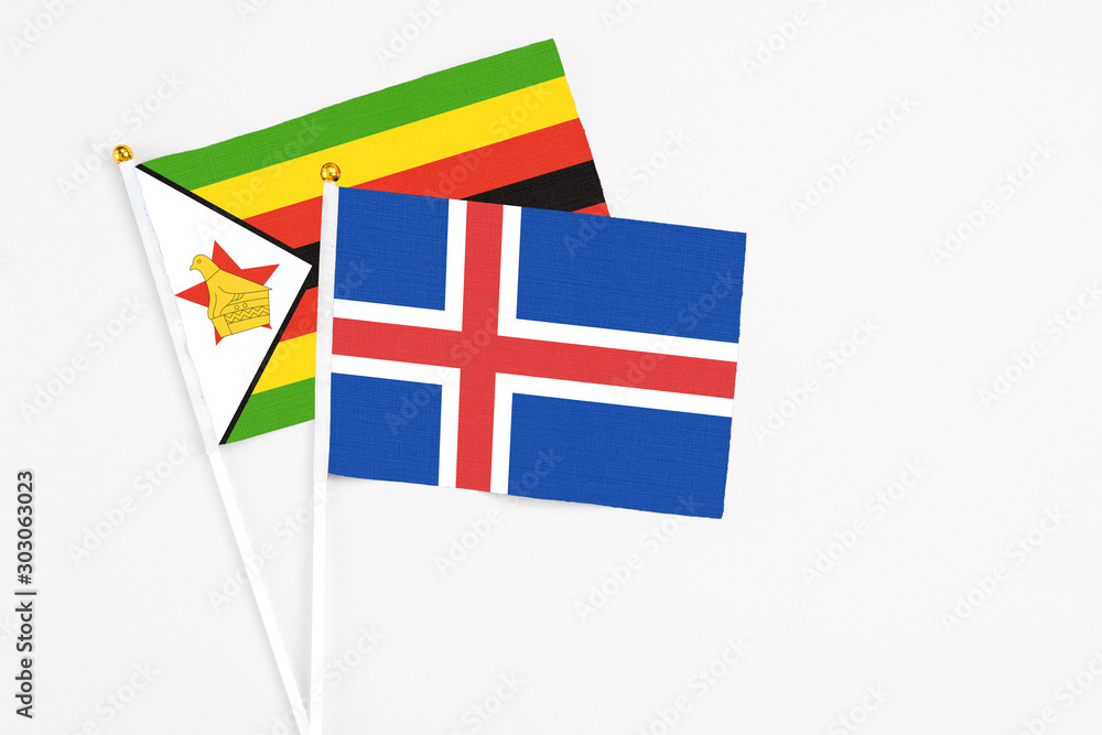 Iceland and Zimbabwe stick flags on white background. High quality fabric, miniature national flag. Peaceful global concept.White floor for copy space.