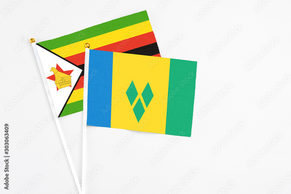 Saint Vincent And The Grenadines and Zimbabwe stick flags on white background. High quality fabric, miniature national flag. Peaceful global concept.White floor for copy space.