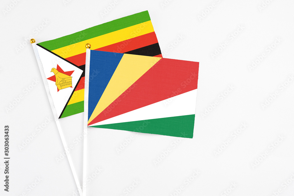 Seychelles and Zimbabwe stick flags on white background. High quality fabric, miniature national flag. Peaceful global concept.White floor for copy space.