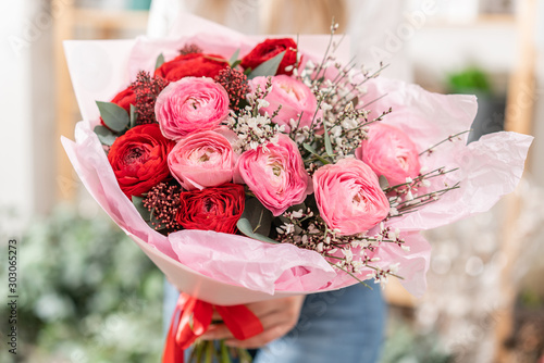 Beautiful bouquet of mixed flowers in womans hands. the work of the florist at a flower shop. Handsome fresh bouquet. Flowers delivery #303065273