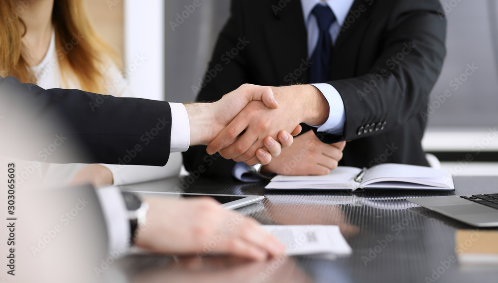 Businessman shaking hands with his colleague or partner above the glass desk in modern office, close-up. Unknown business people at meeting. Teamwork, partnership and handshake concept Businessman shaking hands with his colleague or partner above the glass desk in modern office, close-up. Unknown business people at meeting. Teamwork, partnership and handshake concept