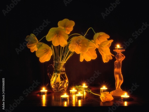 Bouquet of yellow tulips with lighting candles on the black background