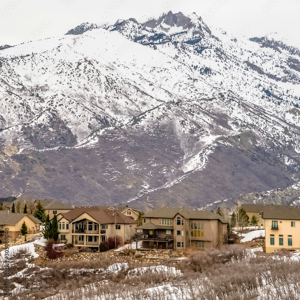 Square Winter landscape with homes on a hill overlooking a striking snowy mountain