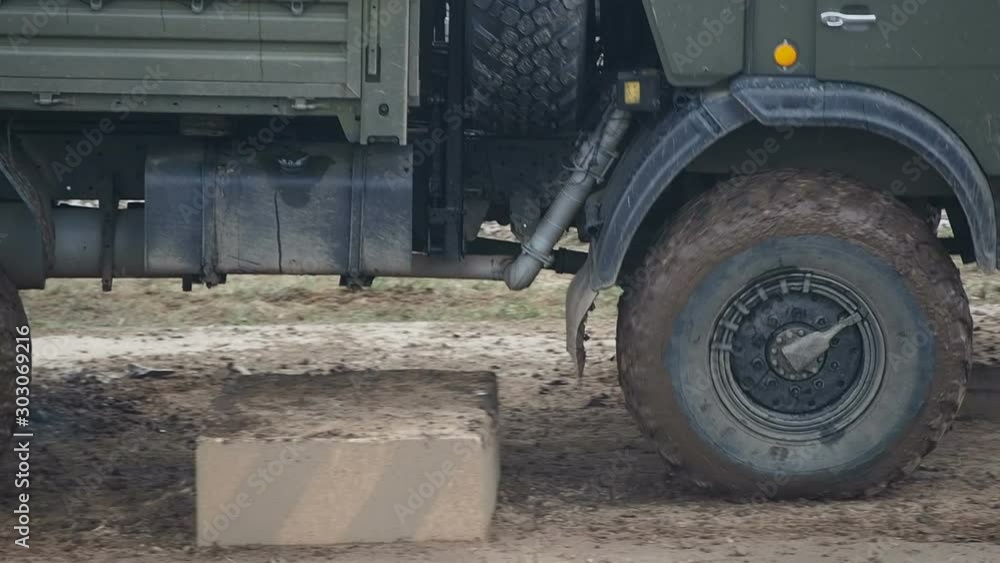 Heavy military off-road truck driving through concrete blocks close-up Heavy military off-road truck driving through concrete blocks close-up