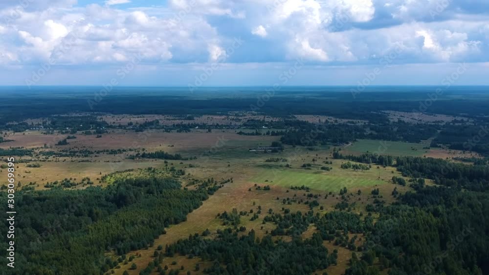 Flying over the field and forest on a summer day, view from the height of the green forest Flying over the field and forest on a summer day, view from the height of the green forest