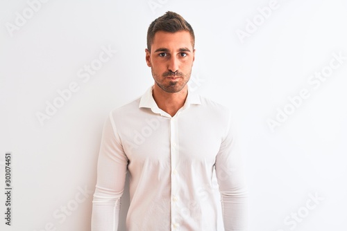 Young handsome business man wearing elegant shirt over isolated background puffing cheeks with funny face. Mouth inflated with air, crazy expression. © Krakenimages.com