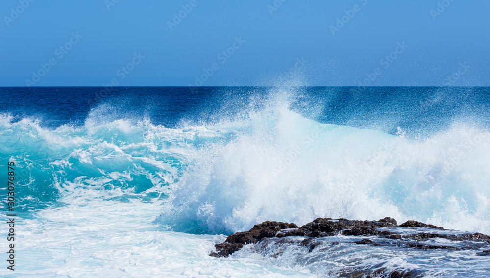 Türkisfarbene Wellen im Atlantik krachen auf einem Felsen der Kanarischen Insel Lanzarote