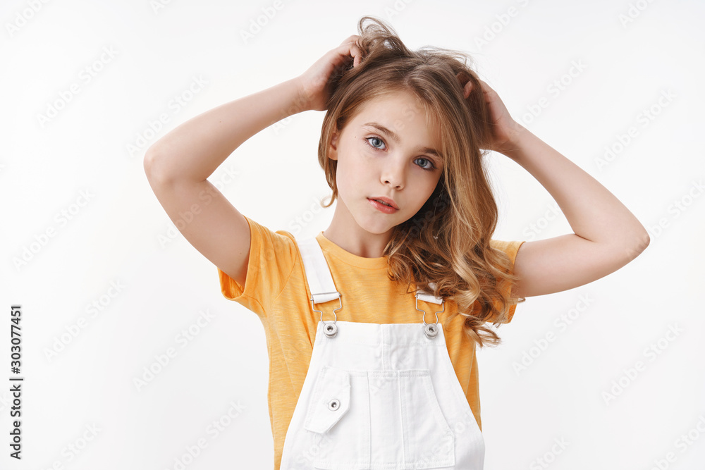 Tender lovely young blond girl in summer dungarees over yellow t-shirt, look thoughtful and cute camera, scratch hair bothered, touch hairstyle, suffer head lice, lacking vitamins, white background Tender lovely young blond girl in summer dungarees over yellow t-shirt, look thoughtful and cute camera, scratch hair bothered, touch hairstyle, suffer head lice, lacking vitamins, white background