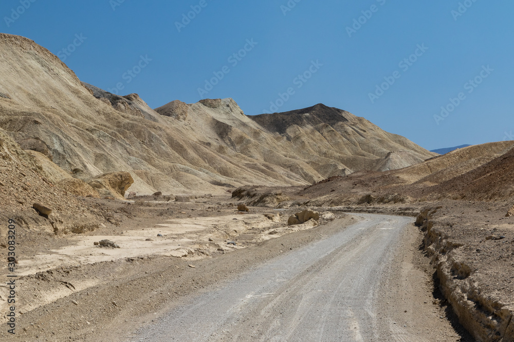 Winding road through golden sandstone formations in Death Valley National Park in California, USA