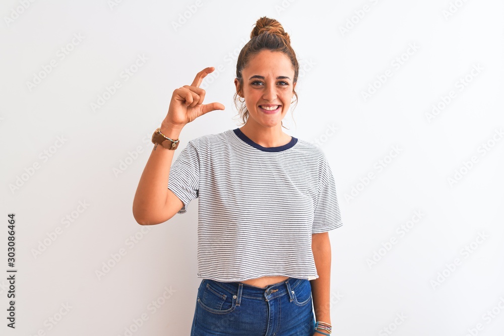Young redhead modern woman wearing a bun over isolated background smiling and confident gesturing with hand doing small size sign with fingers looking and the camera. Measure concept. Young redhead modern woman wearing a bun over isolated background smiling and confident gesturing with hand doing small size sign with fingers looking and the camera. Measure concept.