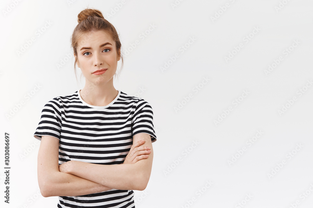 Self-assured confident young skeptical woman with messy bun in striped t-shirt, cross hands chest and smirk feeling superiour and encouraged, stare unconvinced over white background Self-assured confident young skeptical woman with messy bun in striped t-shirt, cross hands chest and smirk feeling superiour and encouraged, stare unconvinced over white background