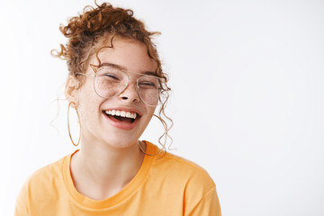 Carefree joyful happy young lucky redhead girl wearing glasses messy curly bun haircut laughing adore awesome funny humor jokes standing delighted white background grinning, white background