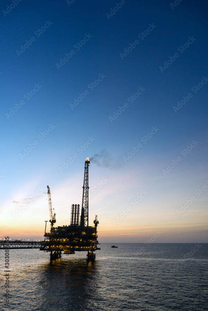 Silhouette of oil production platform during sunset