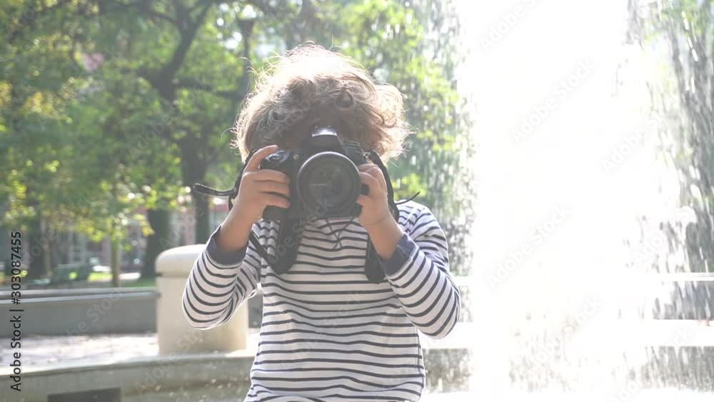 Bambino impara a fotografare con una macchina fotografica reflex professionale in un parco 