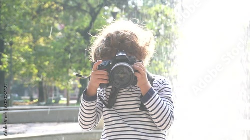Bambino impara a fotografare con una macchina fotografica reflex professionale in un parco  photo
