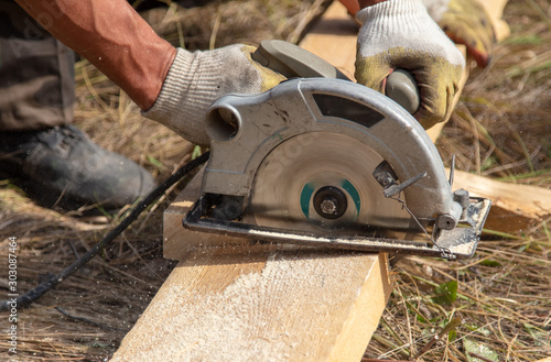 A worker cuts a wooden beam at a construction site