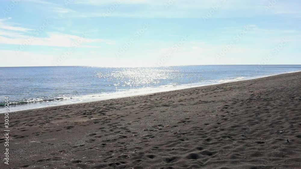 Pan view of black sand Beach footprints on a seashore in Santorini on Greek Islands Pan view of black sand Beach footprints on a seashore in Santorini on Greek Islands