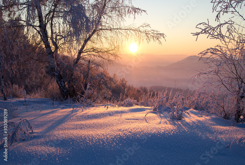 Winter sunset snow mountain view on the background of hills under colorful sky