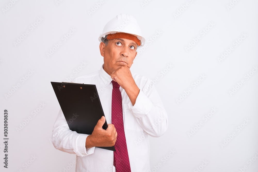 Senior architect man wearing security helmet holding clipboard over isolated white background serious face thinking about question, very confused idea Senior architect man wearing security helmet holding clipboard over isolated white background serious face thinking about question, very confused idea