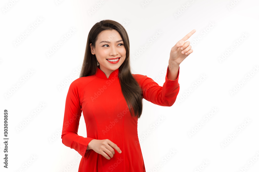 Portrait of young Asian woman wearing a red ao dai and showing hand to somewhere on white background. Portrait of young Asian woman wearing a red ao dai and showing hand to somewhere on white background.