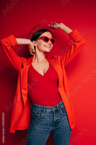Bild auf Leinwand Vertical picture of happy attractive cheerful young woman in red clothes and sunglasses posing on camera
