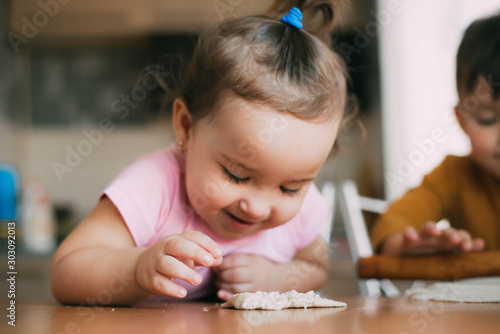 Children, brother and sister during the day in the kitchen prepare pastry or pizza or pie