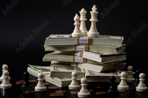 Income inequality, class struggle in capitalism and social issue concept theme with large group of chess pawns representing the poor separated from the wealthy who are sitting on a pile of money photo