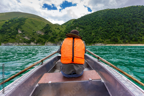 man rowing on a boat back view Beautiful mountain lake Kezenoy Am or Kezenoyam in Chechen republik in Russia
