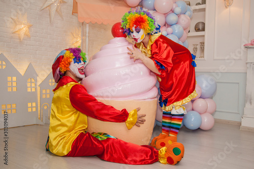 Funny clowns from the circus. Clown boy and clown girl cannot share a cake