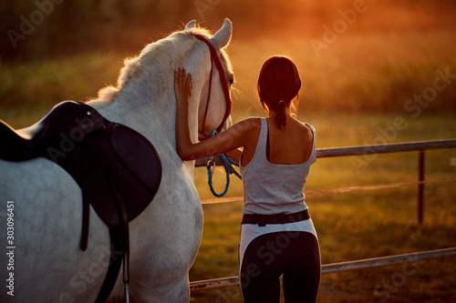 Young woman and her horse enjoying in the calm summer evening
