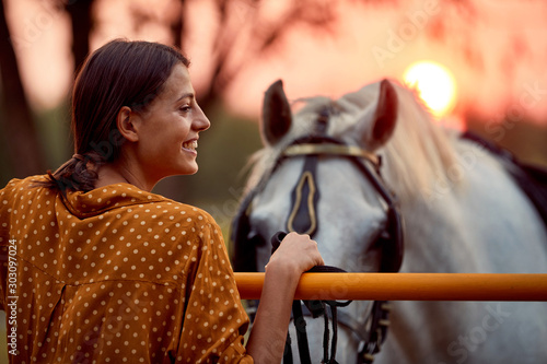 Pretty woman smiling in front of her horse in the sunset © luckybusiness