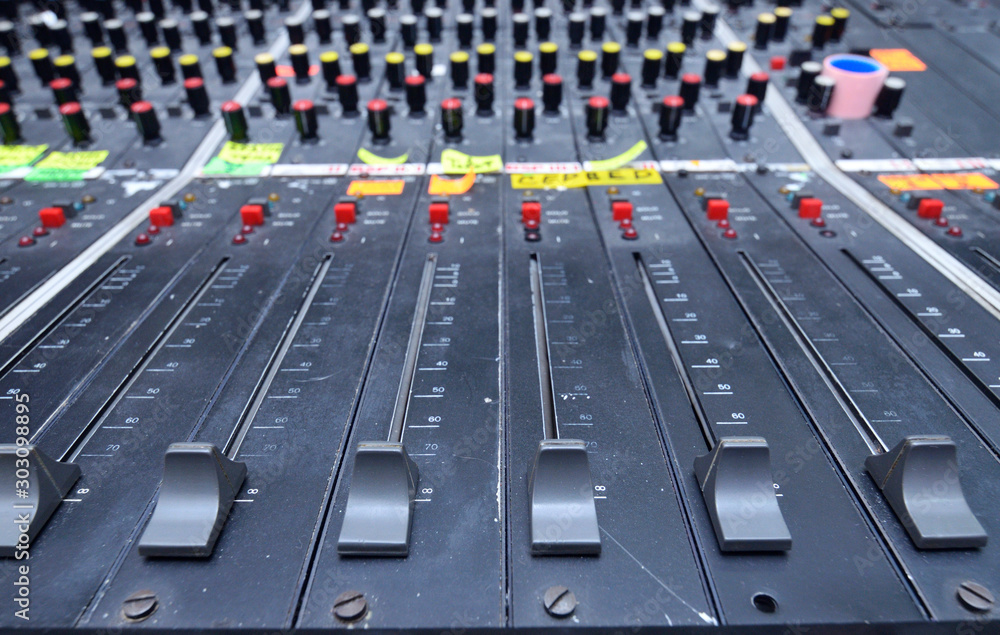 Buttons, levels, switches, speaker volume control on an audio mixer control panel set on a table at a TV studio Buttons, levels, switches, speaker volume control on an audio mixer control panel set on a table at a TV studio