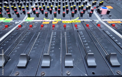 Buttons, levels, switches, speaker volume control on an audio mixer control panel set on a table at a TV studio