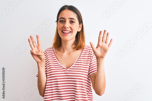 Beautiful redhead woman wearing casual striped red t-shirt over isolated background showing and pointing up with fingers number eight while smiling confident and happy.