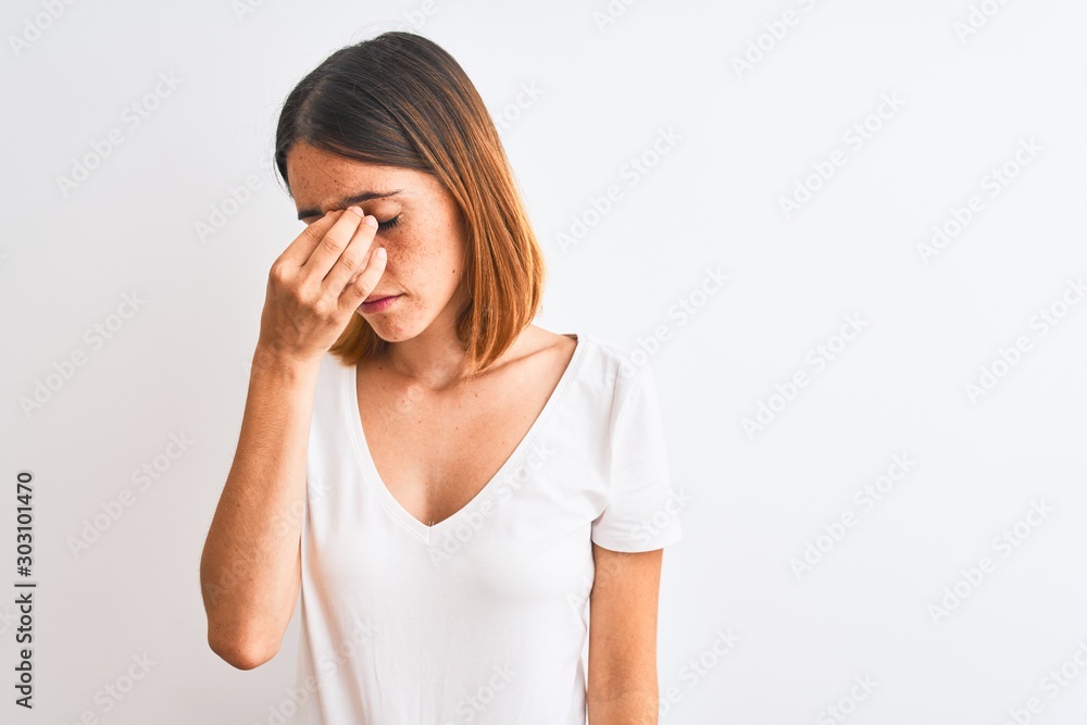Beautiful redhead woman wearing casual white t-shirt over isolated background tired rubbing nose and eyes feeling fatigue and headache. Stress and frustration concept. Beautiful redhead woman wearing casual white t-shirt over isolated background tired rubbing nose and eyes feeling fatigue and headache. Stress and frustration concept.