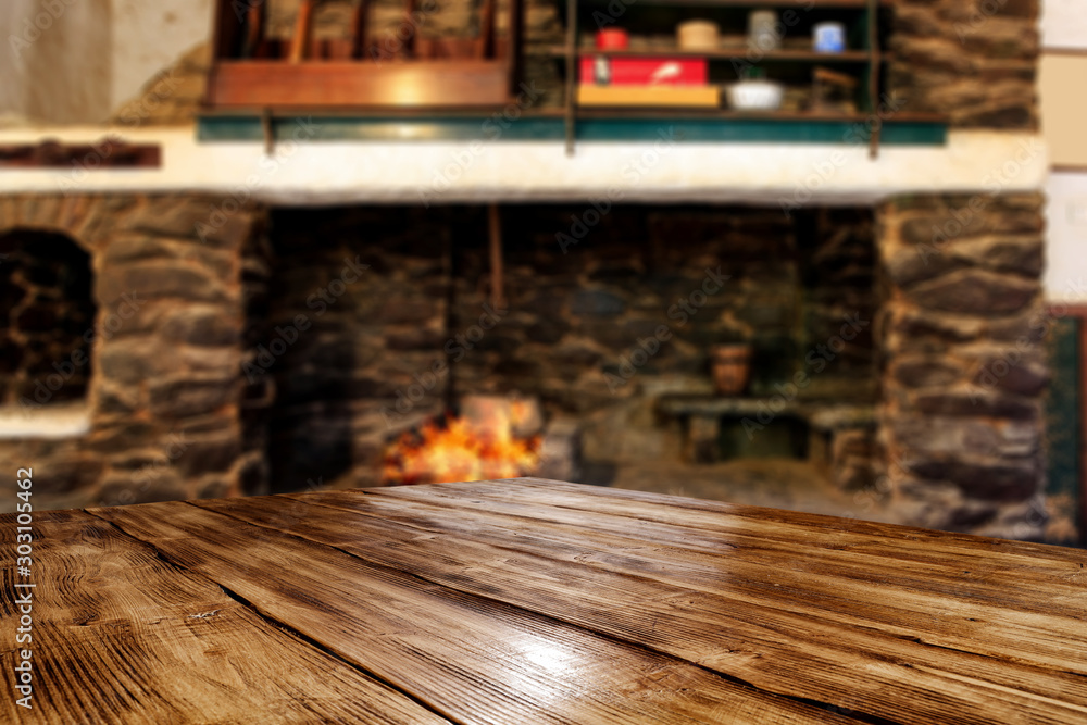 Wooden brown old table desk of free space for your decoration.Christmas fireplace and home interior.Cold december winter time and orange color of warm fire.Copy space and dark mood shadows.