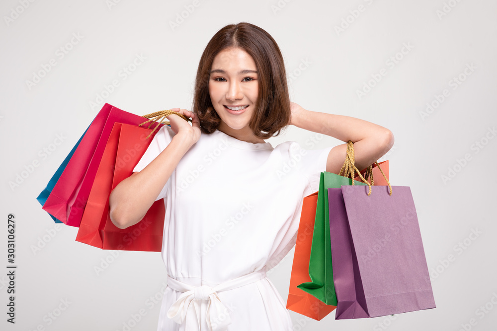 Shopping Asian woman with short hairs smile and Holding Shopping bags,Cheerful and happiness emotional,Enjoy Shopping in black friday sale,Isolated on gray background,Shopping Concept