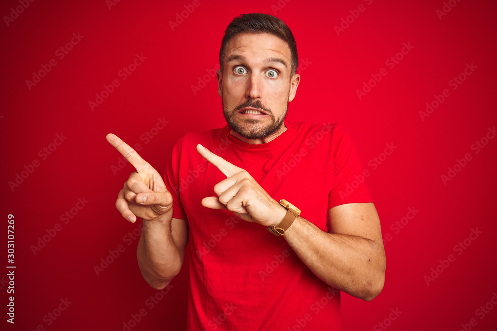 Young handsome man wearing casual t-shirt over red isolated background Pointing aside worried and nervous with both hands, concerned and surprised expression Young handsome man wearing casual t-shirt over red isolated background Pointing aside worried and nervous with both hands, concerned and surprised expression