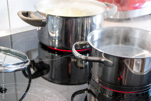 Mittagessen im dampfenden Kochtopf wird auf heißer Herdplatte in der Küche von einer Hausfrau für die Familie gekocht und zubereitet mit Verletzungsgefahr und Verbrennungsgefahr