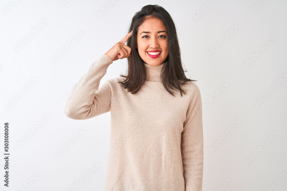 Beautiful chinese woman wearing turtleneck sweater standing over isolated white background Smiling pointing to head with one finger, great idea or thought, good memory Beautiful chinese woman wearing turtleneck sweater standing over isolated white background Smiling pointing to head with one finger, great idea or thought, good memory