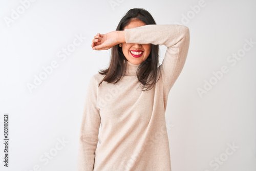 Beautiful chinese woman wearing turtleneck sweater standing over isolated white background covering eyes with arm smiling cheerful and funny. Blind concept.