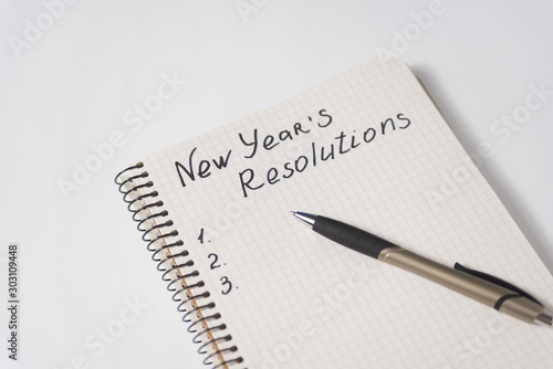 Phrase New Year's resolutions in the notebook and blank page, pen. photo