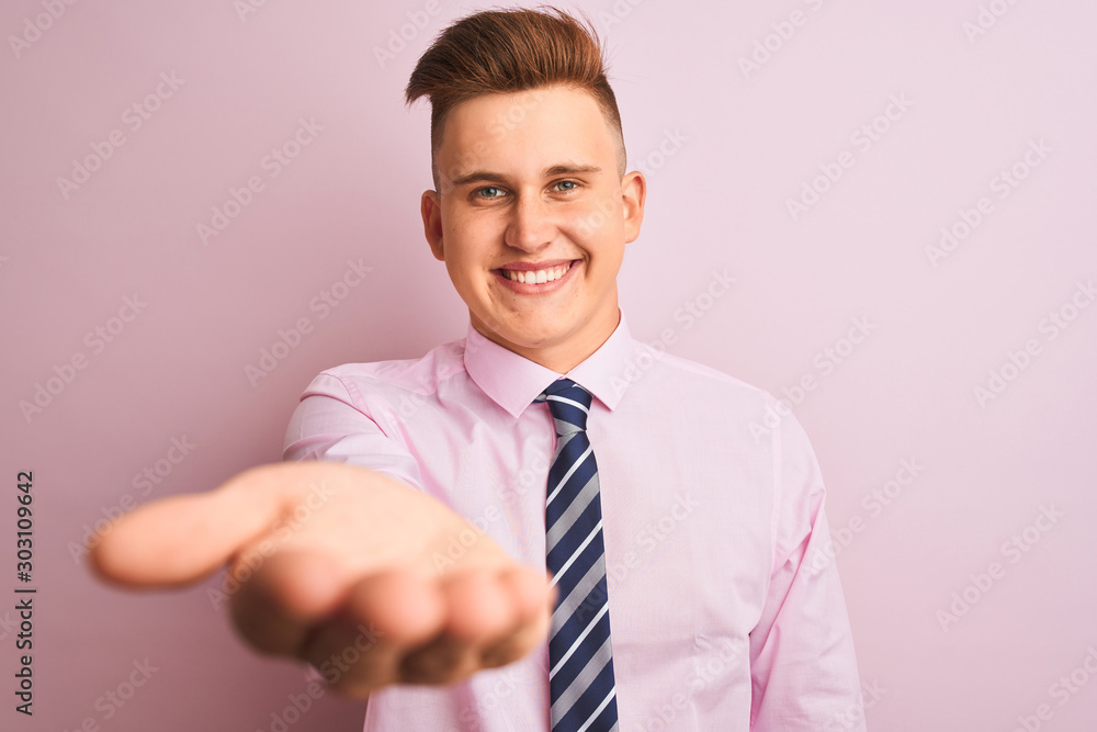Young handsome businessman wearing shirt and tie standing over isolated pink background smiling cheerful offering palm hand giving assistance and acceptance. Young handsome businessman wearing shirt and tie standing over isolated pink background smiling cheerful offering palm hand giving assistance and acceptance.