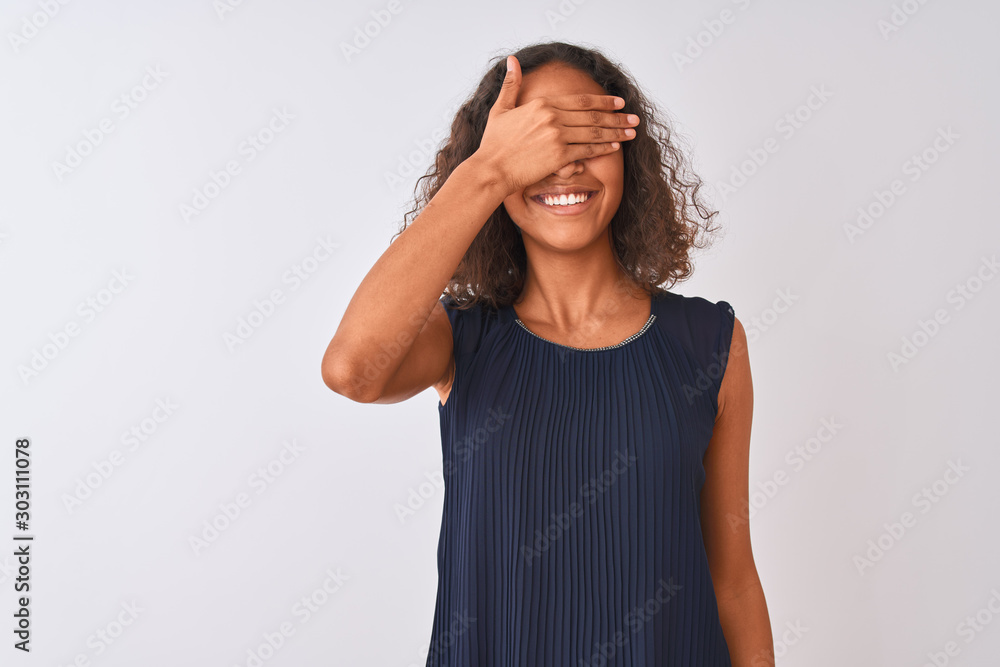 Young brazilian woman wearing blue dress standing over isolated white background smiling and laughing with hand on face covering eyes for surprise. Blind concept. Young brazilian woman wearing blue dress standing over isolated white background smiling and laughing with hand on face covering eyes for surprise. Blind concept.