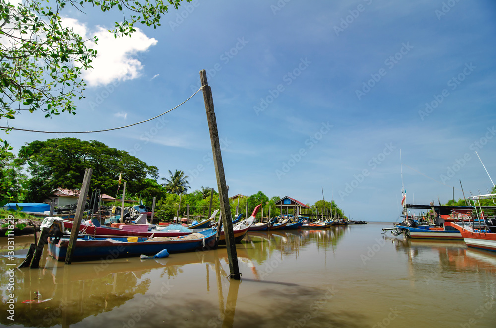 Beautiful rural scenery, fisherman boat moored near wooden jetty over blue sky background