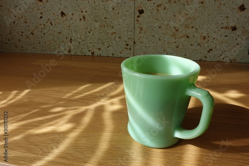 テーブルに置かれたコーヒーカップ　カーテン越しの光の中で　cup of coffee on table