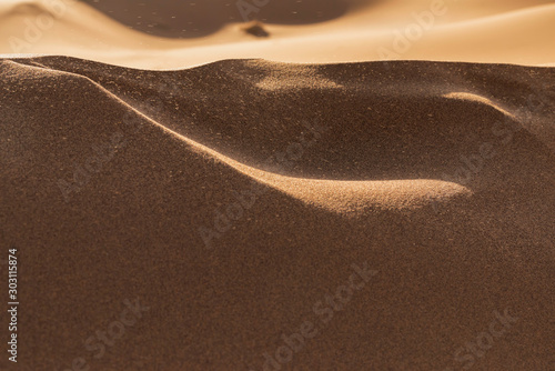 Wind blows sand into the air at the sand dunes of Erg Zahar. photo