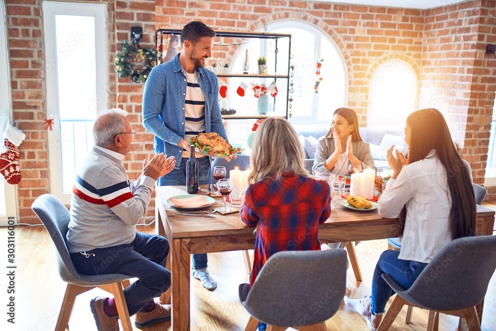 Beautiful family meeting smiling happy and confident. Person standing holding roasted turkey celebrating Christmas at home Beautiful family meeting smiling happy and confident. Person standing holding roasted turkey celebrating Christmas at home