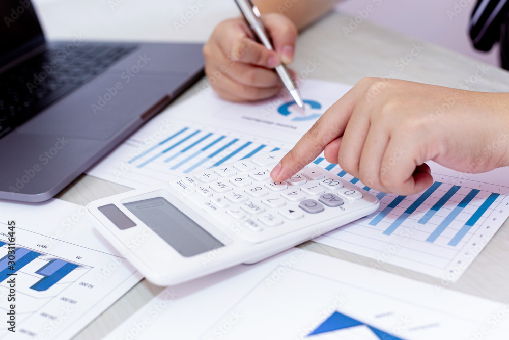 Business financial and investment concepts, people using calculators and data graphs to analyze company revenue and expenditures in preparation for the planning of presentations, finances concept Business financial and investment concepts, people using calculators and data graphs to analyze company revenue and expenditures in preparation for the planning of presentations, finances concept