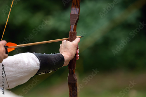 Archer holds his bow aiming at the target. Archery competition, outdoor activity